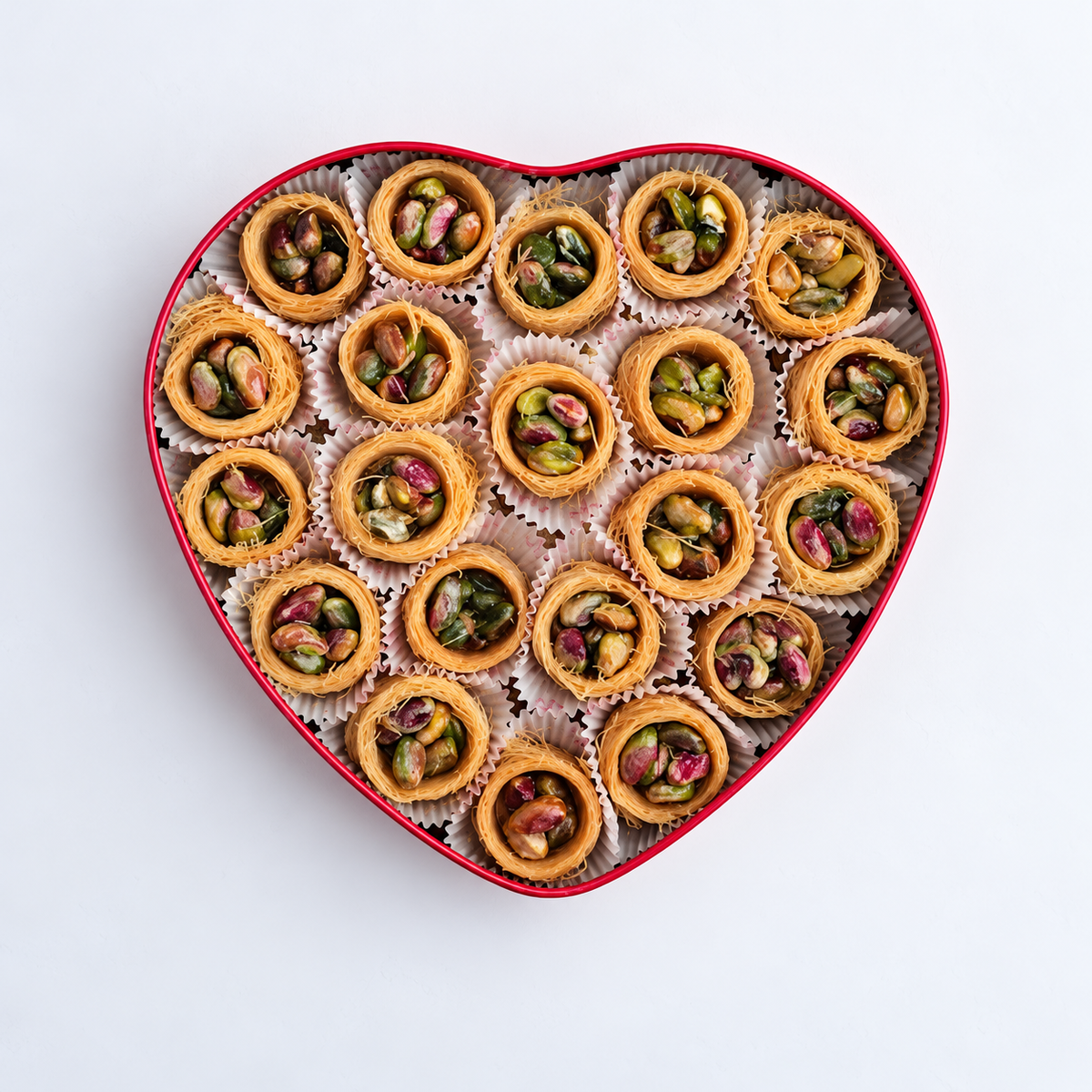 Douaihy Heart Tin Ich El Bilbol ~ 40pcs. Pistachio-filled pastry nests in a pink heart-shaped tin viewed from above.