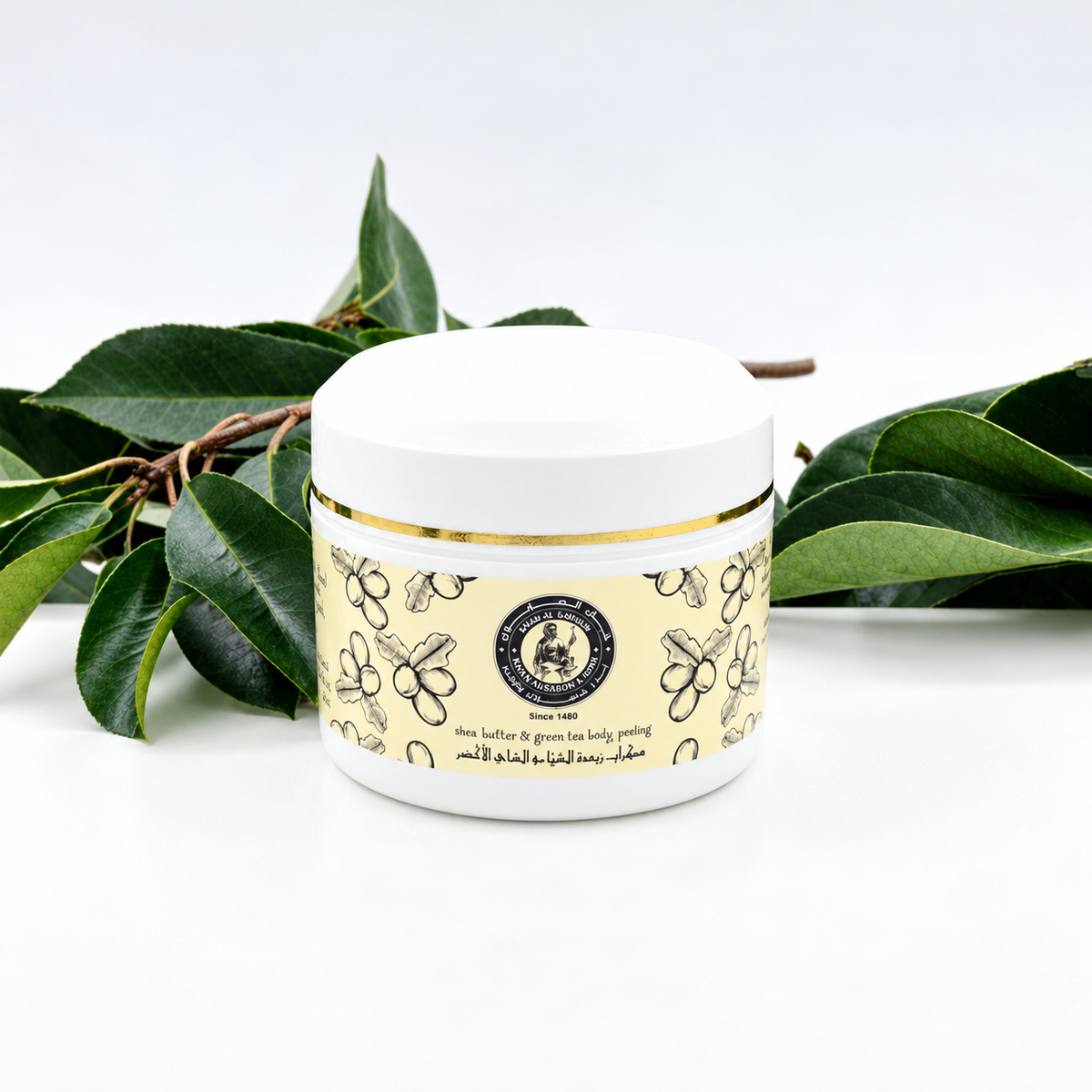 Khan Al Saboun Shea Butter with Green Tea Scrub – 150g. White scrub jar with botanical label and green leaves.