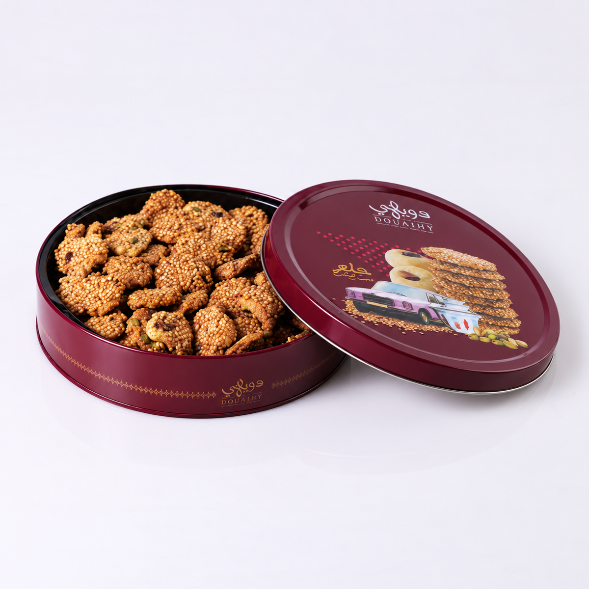 Douaihy Round Tin Barazek ~ 150pcs. Sesame barazek cookies in an open burgundy round tin with illustrated lid.