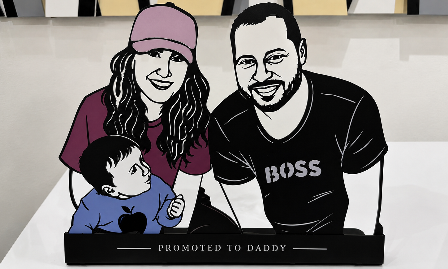 Decorative plaque with illustrations of a family and text 'Promoted to Daddy' on a white surface.