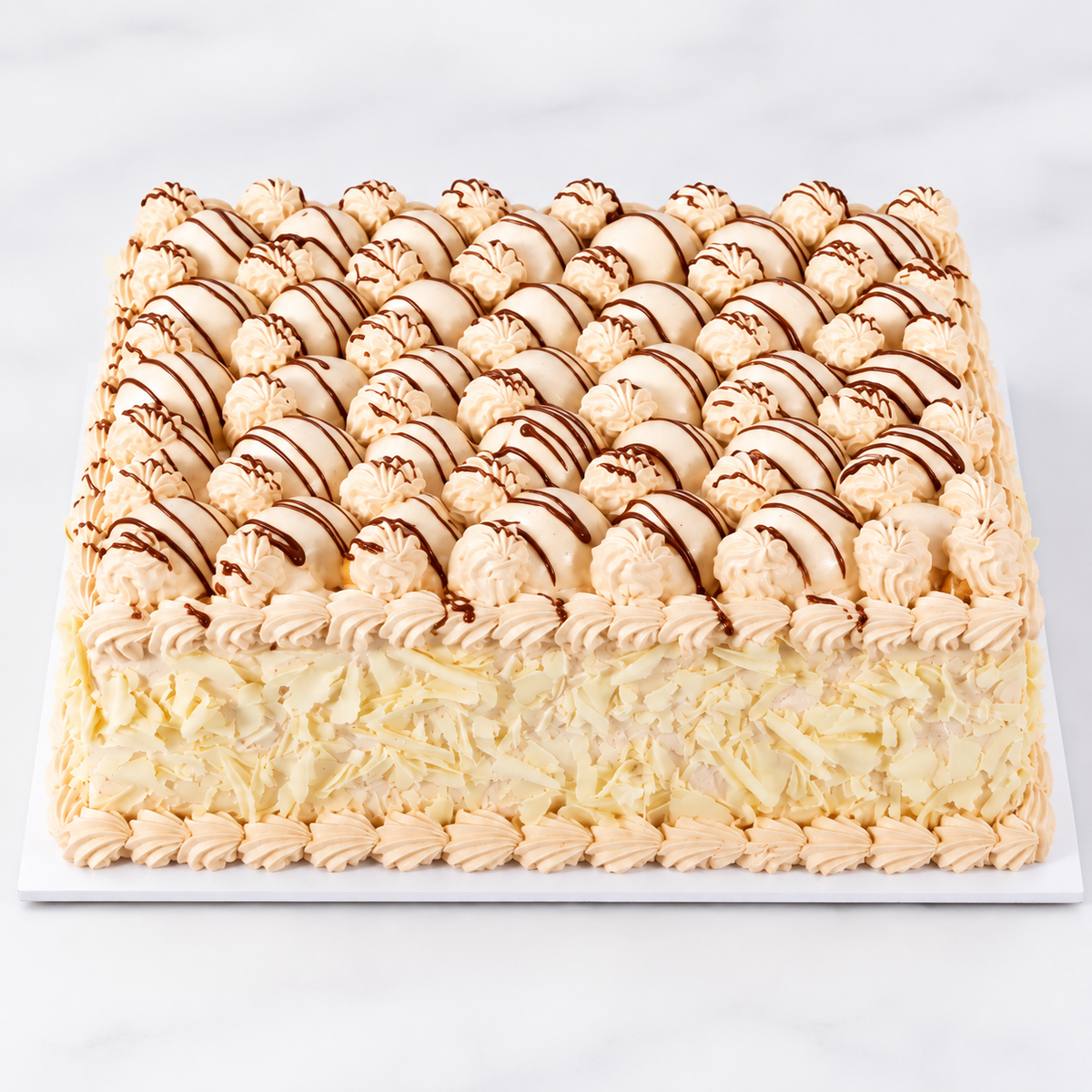 Rectangular Cortina Praline cake with cream-covered profiteroles and chocolate drizzle