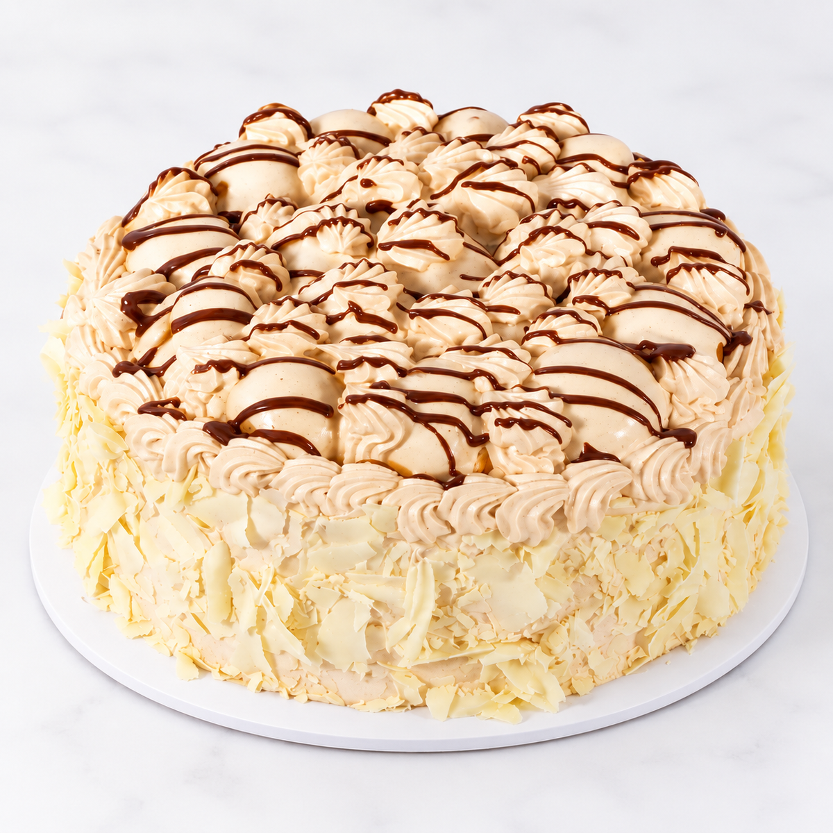 Round Cortina Praline cake with cream-covered profiteroles and chocolate drizzle
